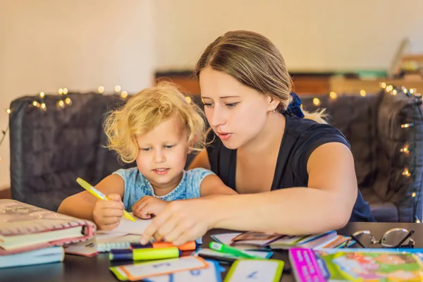 Un profesor, un tutor para la educación en casa y un profesor en la mesa. O mamá y su hija. Educación en el hogar — Foto de Stock