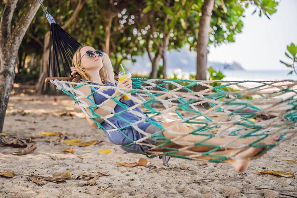 Mujer joven en la playa en una hamaca con una bebida —  Fotos de Stock