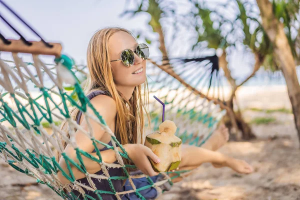 Giovane donna sulla spiaggia su un'amaca con un drink — Foto Stock