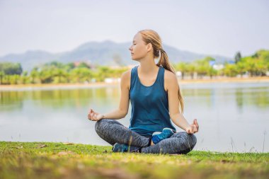 Tropik bir parkta yoga yapan bir kadın.