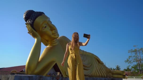 慢动作拍摄一名年轻女旅行者参观寺斯里松索恩寺庙与躺在佛陀雕像在普吉岛。前往泰国的概念 — 图库视频影像