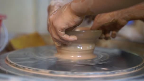 Slowmotion close-up tiro de um professor oleiro ensinando seu aprendiz como fazer uma tigela de barro em uma roda Potters — Vídeo de Stock