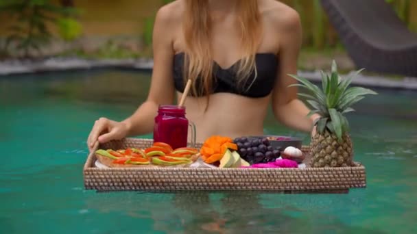 Молода жінка-туристка має свій особистий сніданок на плавальному столі в приватному басейні. Тропічний пляжний спосіб життя — стокове відео
