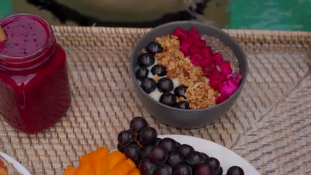 A young woman tourist has her own personal breakfast on a floating table in a private swimming pool. Tropical beach lifestyle — Stock Video