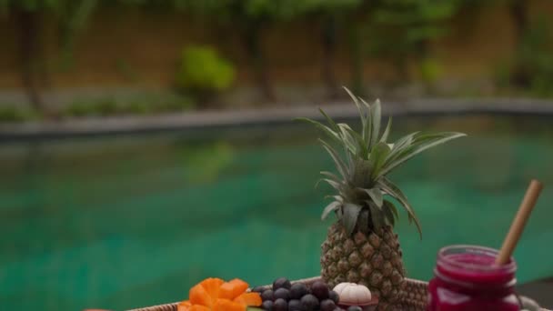 Tiro de perto de um café da manhã pessoal em uma mesa flutuante em uma piscina privada. Estilo de vida tropical na praia — Vídeo de Stock