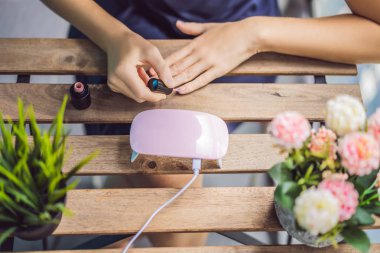 Genç kadın pembe tonlarında jel cila ve Uv lamba ile manikür yapar