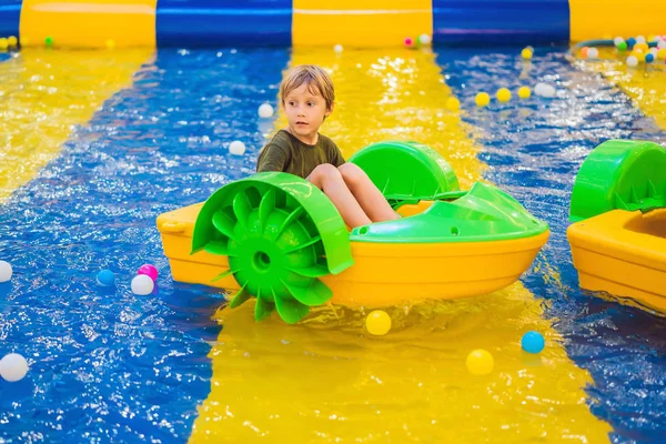 Szczęśliwy młody chłopak na łodzi ciesząc się grając na parku rozrywki — Zdjęcie stockowe