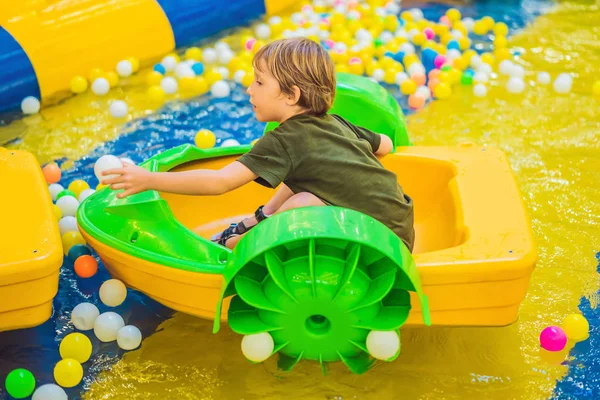 Счастливый мальчик на лодке наслаждается игрой в парке развлечений — стоковое фото
