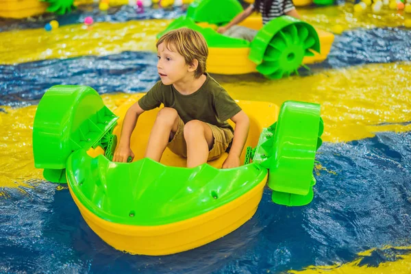 Onnellinen nuori poika veneessä nauttii leikkimisestä huvipuistossa — kuvapankkivalokuva