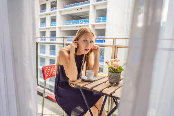 Ung kvinna på balkongen irriterade av byggnaden fungerar utanför. Brus koncept. Luftföroreningar från att bygga damm — Stockfoto