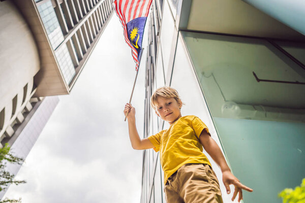Young boy tourist with the flag of Malaysia near the skyscrapers. Traveling with kids concept