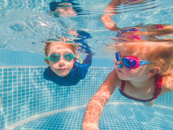 Crianças se divertindo jogando debaixo d 'água na piscina nas férias de verão — Fotografia de Stock