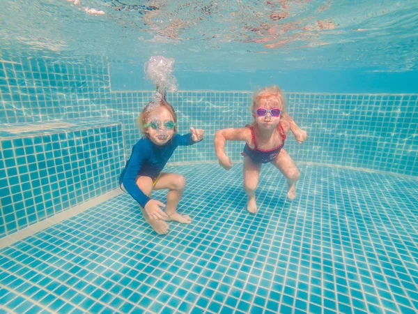 Niños divirtiéndose jugando bajo el agua en la piscina en las vacaciones de verano — Foto de Stock