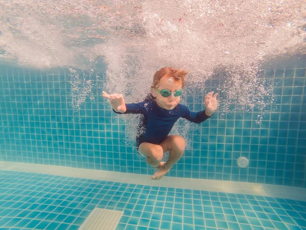 Menino se divertindo jogando debaixo d 'água na piscina em férias de verão — Fotografia de Stock