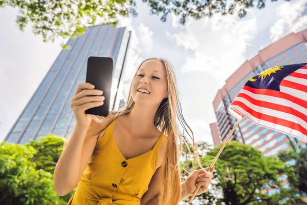 Utazás és a technológia. Fiatal nő turista a zászló Malajzia nézi a Várostérkép egy okostelefon a navigáció — Stock Fotó