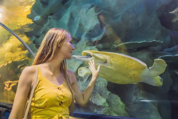 Jeune femme touche un poisson raie dans un tunnel océanique — Photo