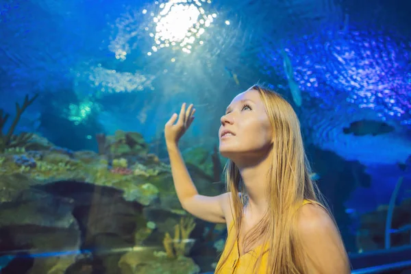 Jonge vrouw raakt een pijlstaartrog vis in een oceanarium tunnel aan — Stockfoto