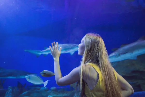 Jeune femme touche un poisson raie dans un tunnel océanique — Photo