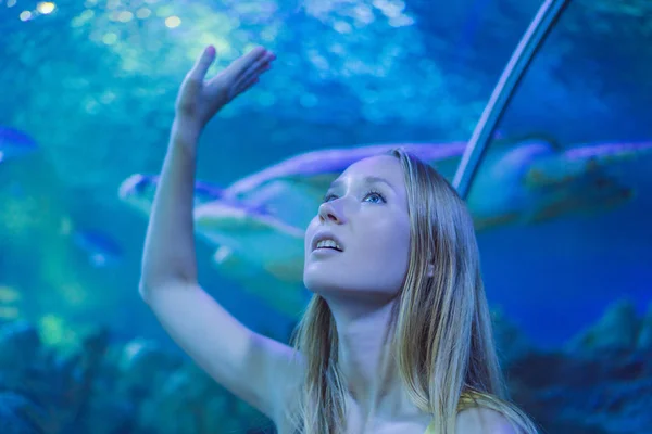 Egy fiatal nő megérint egy rája halat egy óceáni alagútban. — Stock Fotó