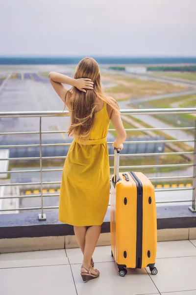 Beginn ihrer Reise. Schöne junge Frau im gelben Kleid und gelbem Koffer wartet auf ihren Flug — Stockfoto