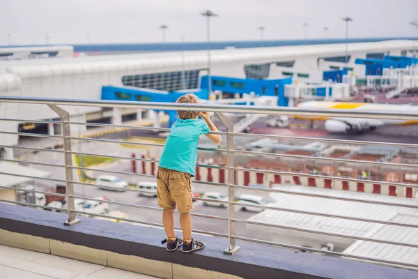 Family at airport before flight. Boy waiting to board at departure gate of modern international terminal. Traveling and flying with children. Kid boarding airplane