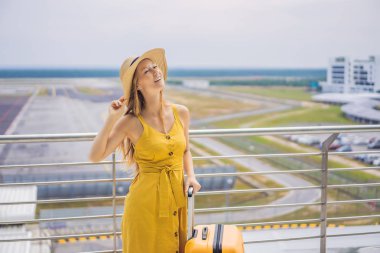 Yolculuğunun başlangıcı. Sarı bir elbise ve sarı bir bavul içinde güzel genç kadın ltraveler onu uçuş bekliyor