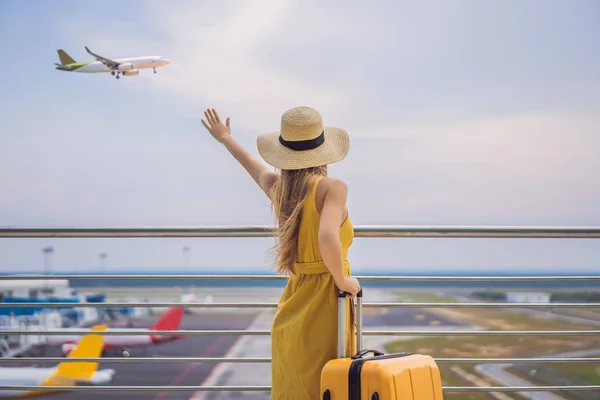 Comienzo de su viaje. Hermosa joven viajera en un vestido amarillo y una maleta amarilla está esperando su vuelo —  Fotos de Stock