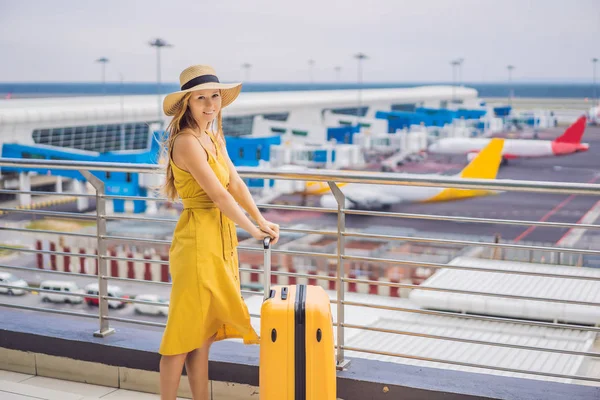 Rozpoczęcie podróży. Piękna młoda kobieta ltraveler w żółtej sukni i żółta walizka czeka na jej lot — Zdjęcie stockowe