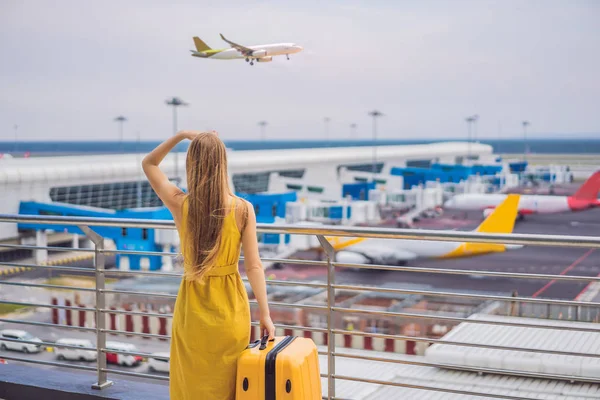 Beginn ihrer Reise. Schöne junge Frau im gelben Kleid und gelbem Koffer wartet auf ihren Flug — Stockfoto