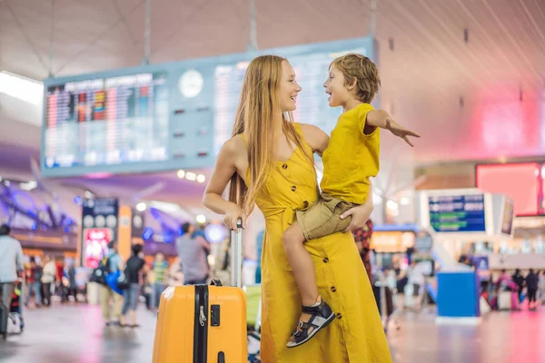 Family at airport before flight. Mother and son waiting to board at departure gate of modern international terminal. Traveling and flying with children. Mom with kid boarding airplane. yellow family