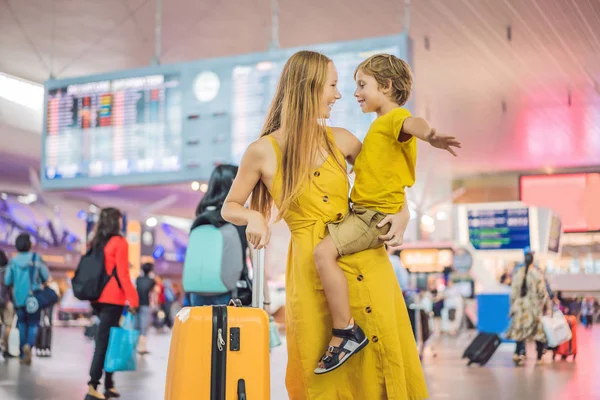 Familie vor dem Abflug am Flughafen. Mutter und Sohn warten am Abfluggate des modernen internationalen Terminals darauf, an Bord zu gehen. Reisen und Fliegen mit Kindern. Mutter mit Kind steigt in Flugzeug. gelbe Familie — Stockfoto