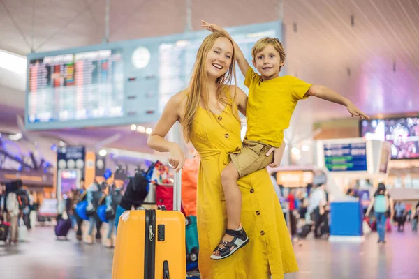 Familie vor dem Abflug am Flughafen. Mutter und Sohn warten am Abfluggate des modernen internationalen Terminals darauf, an Bord zu gehen. Reisen und Fliegen mit Kindern. Mutter mit Kind steigt in Flugzeug. gelbe Familie — Stockfoto