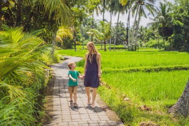 Anne ve oğlu pirinç terasları, Ubud, Bali, Endonezya arka planda pirinç alanında. Çocuk konsepti ile seyahat. Uygulamada çocuklara güneş ışığı ile eğitim