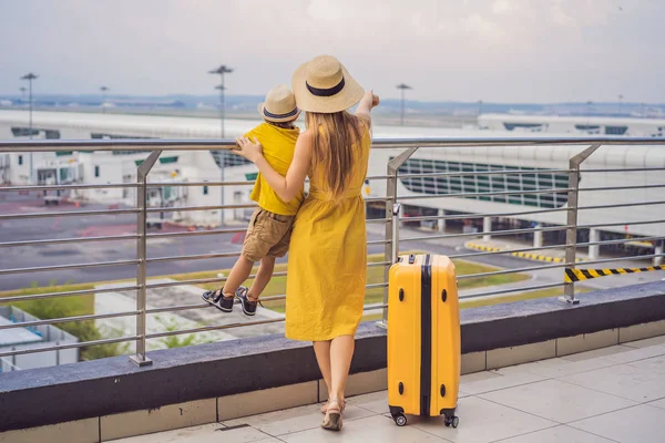 Familie vor dem Abflug am Flughafen. Mutter und Sohn warten am Abfluggate des modernen internationalen Terminals darauf, an Bord zu gehen. Reisen und Fliegen mit Kindern. Mutter mit Kind steigt in Flugzeug. gelbe Familie — Stockfoto