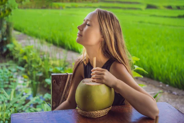 Junge Frau mit frischem Kokoscocktail im Hintergrund eines Reisfeldes — Stockfoto