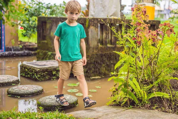 Boy walking on tiles in a pond — Stock Photo, Image