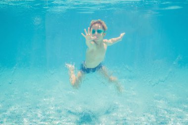 Yaz tatilinde yüzme havuzunda su altında oynarken eğlenen çocuk