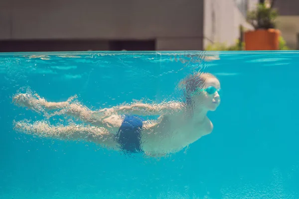 Menino se divertindo jogando debaixo d 'água na piscina em férias de verão — Fotografia de Stock