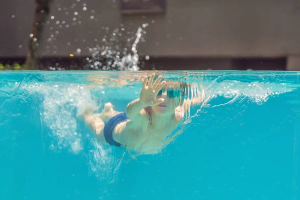 Menino se divertindo jogando debaixo d 'água na piscina em férias de verão — Fotografia de Stock