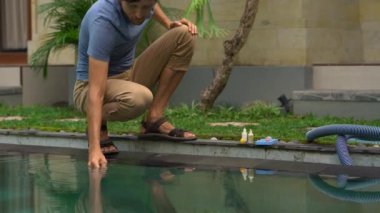 Genç adam yüzme havuzunda klor, ph ve diğer kimyasal seviyeleri kontrol ediyor.