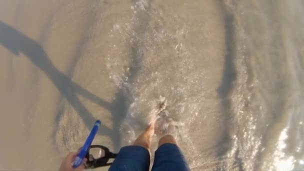 Суперснимок человека, который ходит по морским волнам, держа в руке маску для снорклинга — стоковое видео