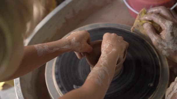 Slowmotion close-up tiro de um professor oleiro ensinando seu aprendiz como fazer uma tigela de barro em uma roda Potters — Vídeo de Stock