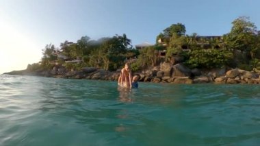 Küçük oğlunu denize sokan genç bir babanın süper yavaş hareket çekimi. Yaz konsepti. Çocuk konsepti ile seyahat