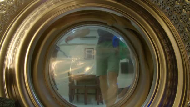 View from the washing machine as a young man puts dirty clothes into it — Stock Video