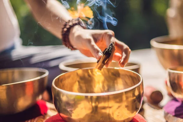 Vrouw spelen op Tibetaanse Singing Bowl terwijl zittend op yoga mat tegen een waterval. Vintage tonned. Mooi meisje met Mala kralen mediteren — Stockfoto