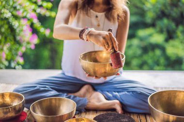 Tibet'te bir şelaleye karşı yoga minderinde otururken çalan kadın. Vintage tonlu. Mala boncuk meditasyon ile güzel kız