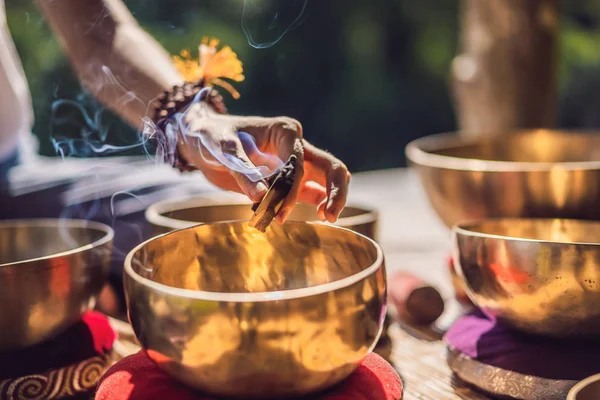 Vrouw spelen op Tibetaanse Singing Bowl terwijl zittend op yoga mat tegen een waterval. Vintage tonned. Mooi meisje met Mala kralen mediteren — Stockfoto