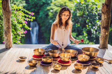 Tibet'te bir şelaleye karşı yoga minderinde otururken çalan kadın. Vintage tonlu. Mala boncuk meditasyon ile güzel kız