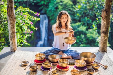 Tibet'te bir şelaleye karşı yoga minderinde otururken çalan kadın. Vintage tonlu. Mala boncuk meditasyon ile güzel kız