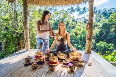 Spa salonunda Nepal Buda bakır kasesi. Genç, güzel bir kadın masaj terapisi yapıyor. Spa 'da şelaleye karşı kâseler söylüyor. Ses terapisi, dinlenme, meditasyon, sağlıklı yaşam tarzı ve...